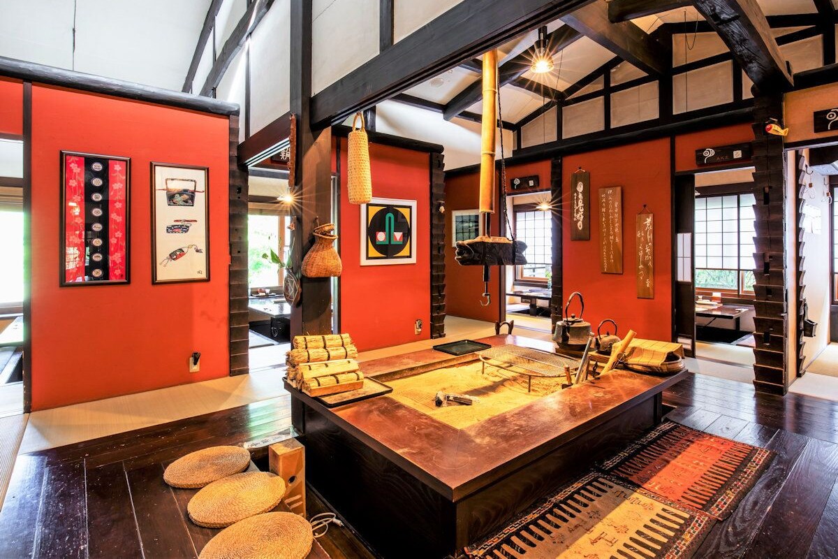 A spacious room with a large wooden table, red walls, and traditional decor.
