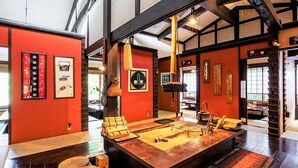 Una habitación amplia con una gran mesa de madera, paredes rojas y decoración tradicional.