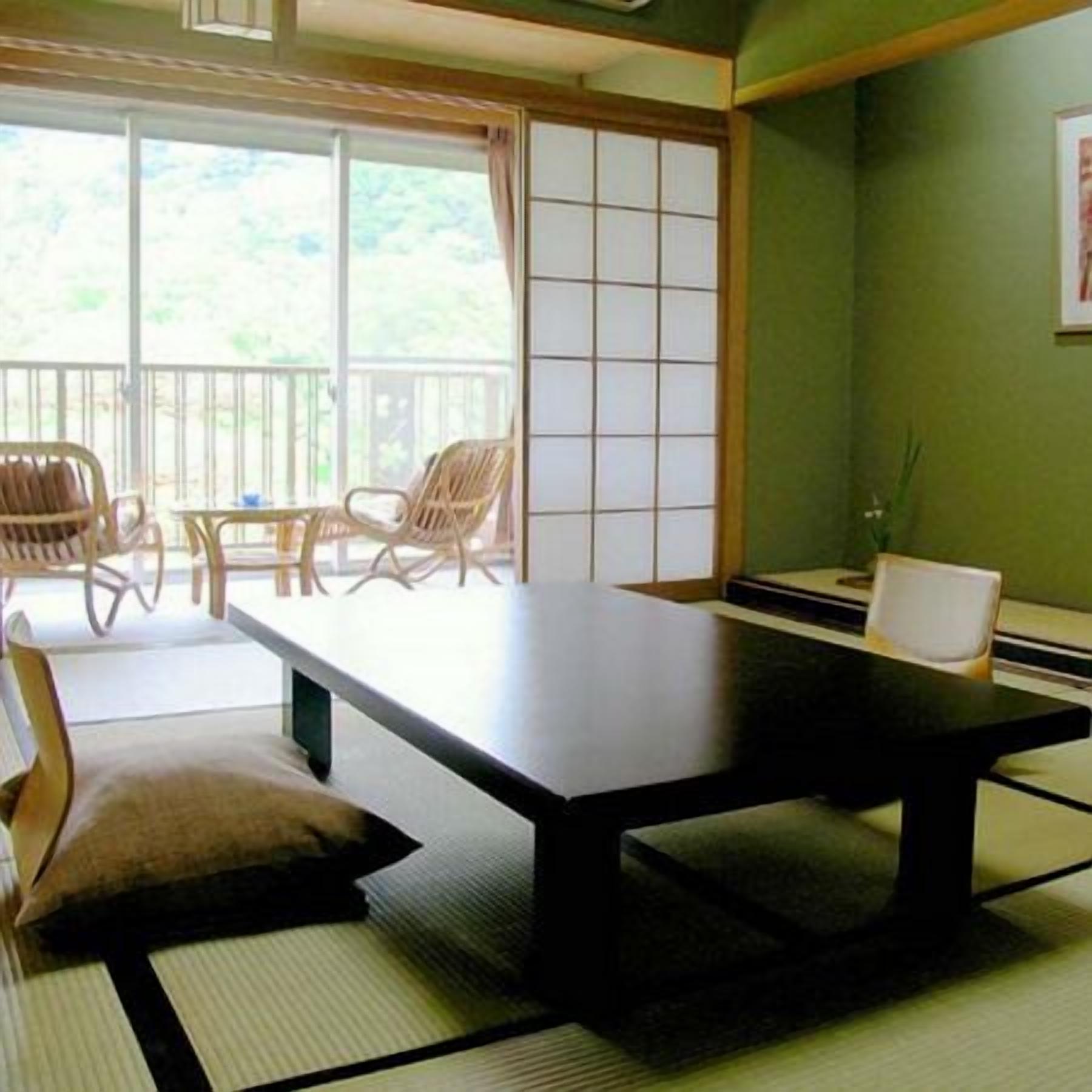 Ein traditioneller japanischer Raum mit Tatami-Boden, einem niedrigen Tisch und einer Balkonühung durch verschiebbare Türen.