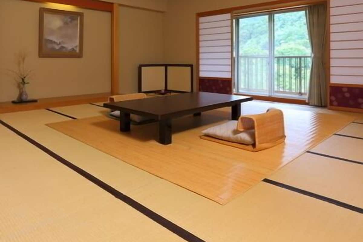 A tatami mat room with a low table, a cushion, and a painting on the wall.