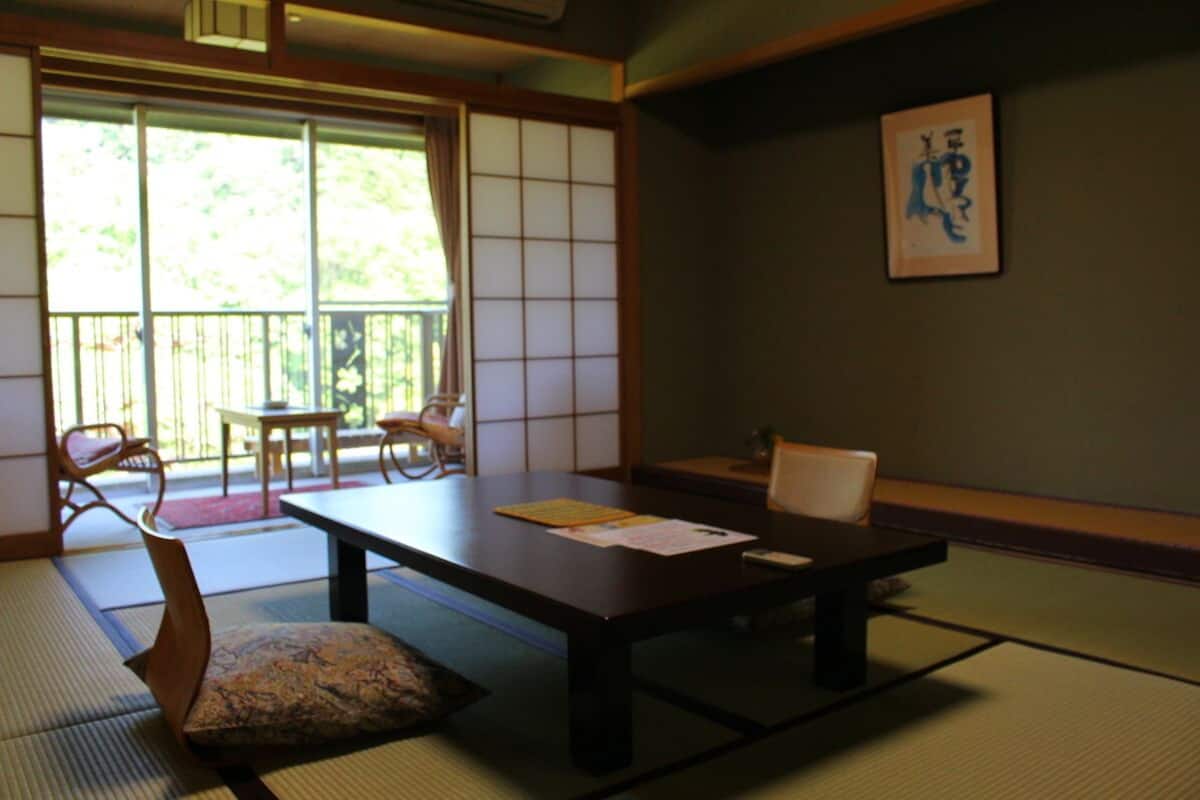 A traditional Japanese room with tatami flooring, a low table, and sliding doors.