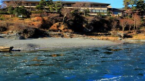 Un río con una embarcación, un edificio de varios pisos y un promontorio rocoso con árboles.
