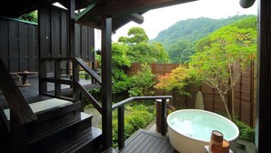 Una terraza de madera con un jacuzzi y vistas a una montaña boscosa.