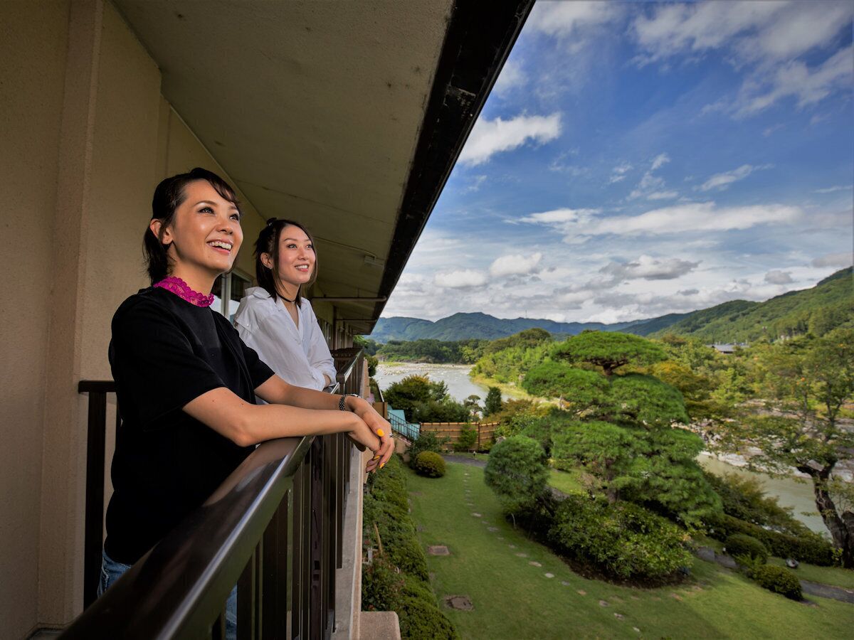 A balcony with a view of a river and greenery.