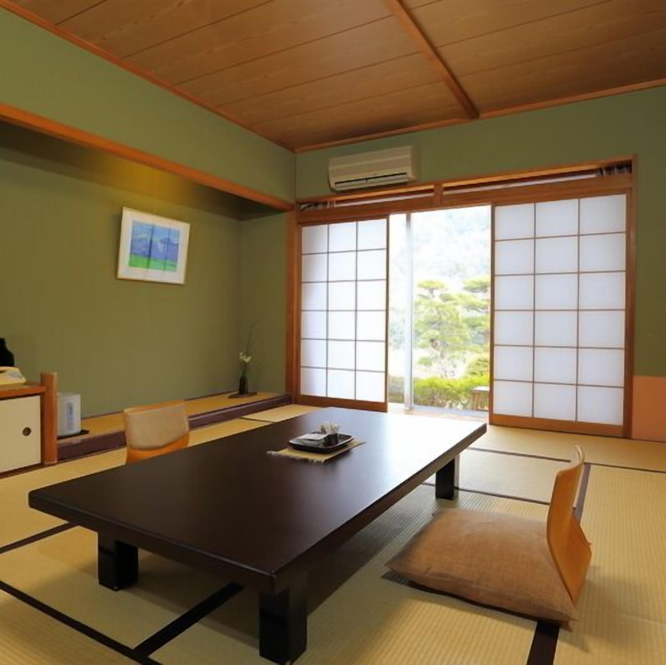 Ein traditioneller japanischer Raum mit Tatami-Bodenbelag, einem niedrigen Tisch, einem Stuhl und einer schiebbaren Shoji-Schiebetür.