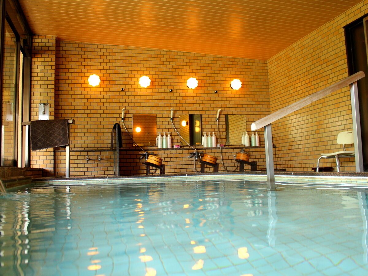 Ein Innenpool mit Backsteinwand, Holzbalkendecke und einer Bank.