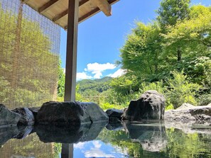 A serene outdoor setting with a wooden structure, a clear sky, and lush greenery.
