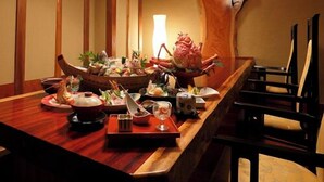 A wooden dining table with various dishes, a large wooden fish sculpture, and traditional Japanese decor.
