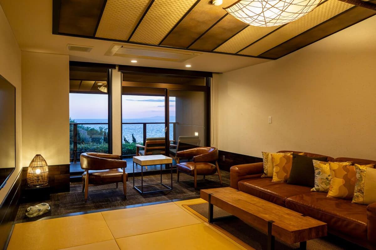 Ein modernes Wohnzimmer mit einer Ledersofa, einem Holztisch und Meerblick durch große Fenster.