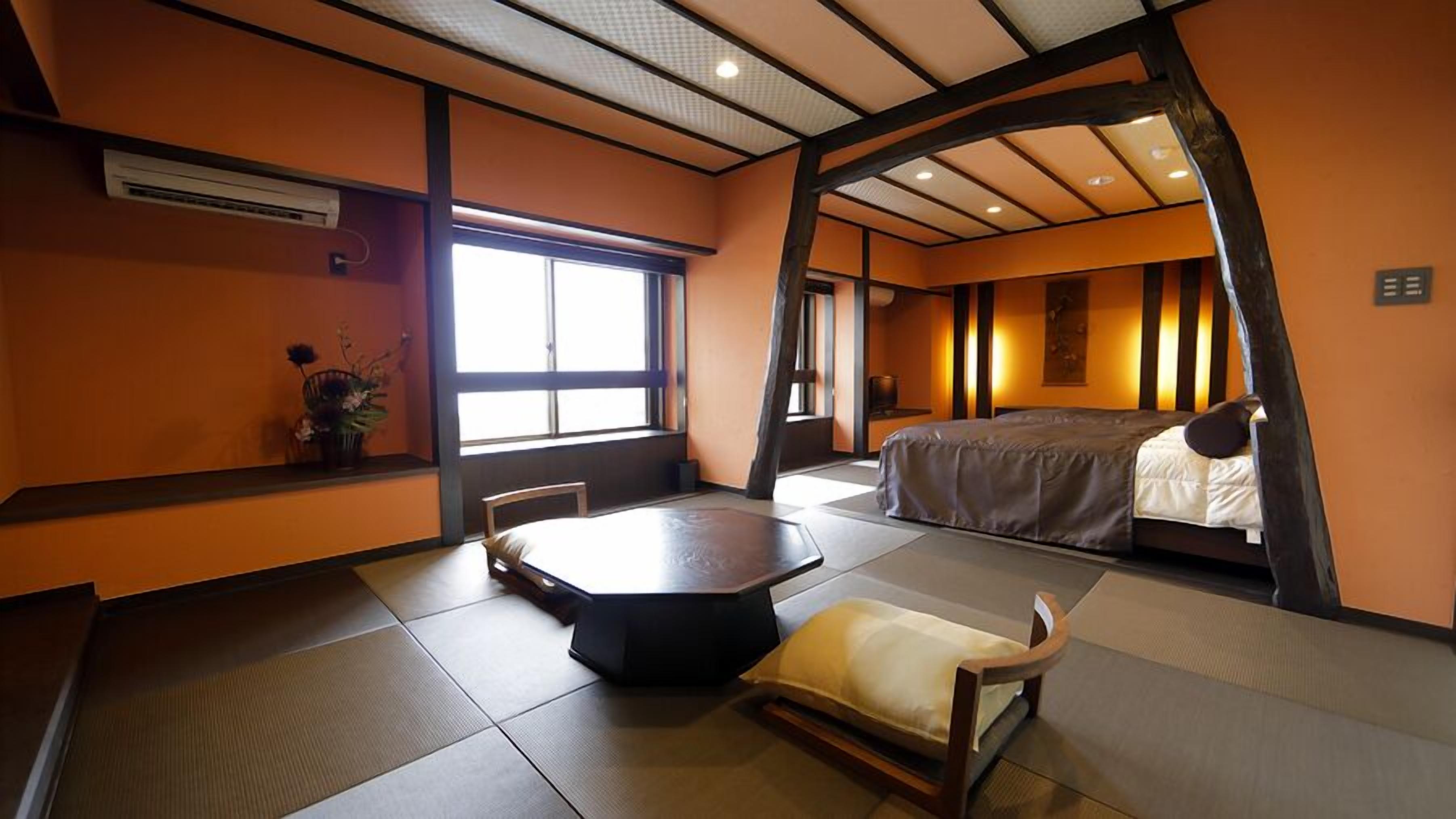 A traditional Japanese-style room with tatami flooring, a low table, a bed, and a window providing natural light.