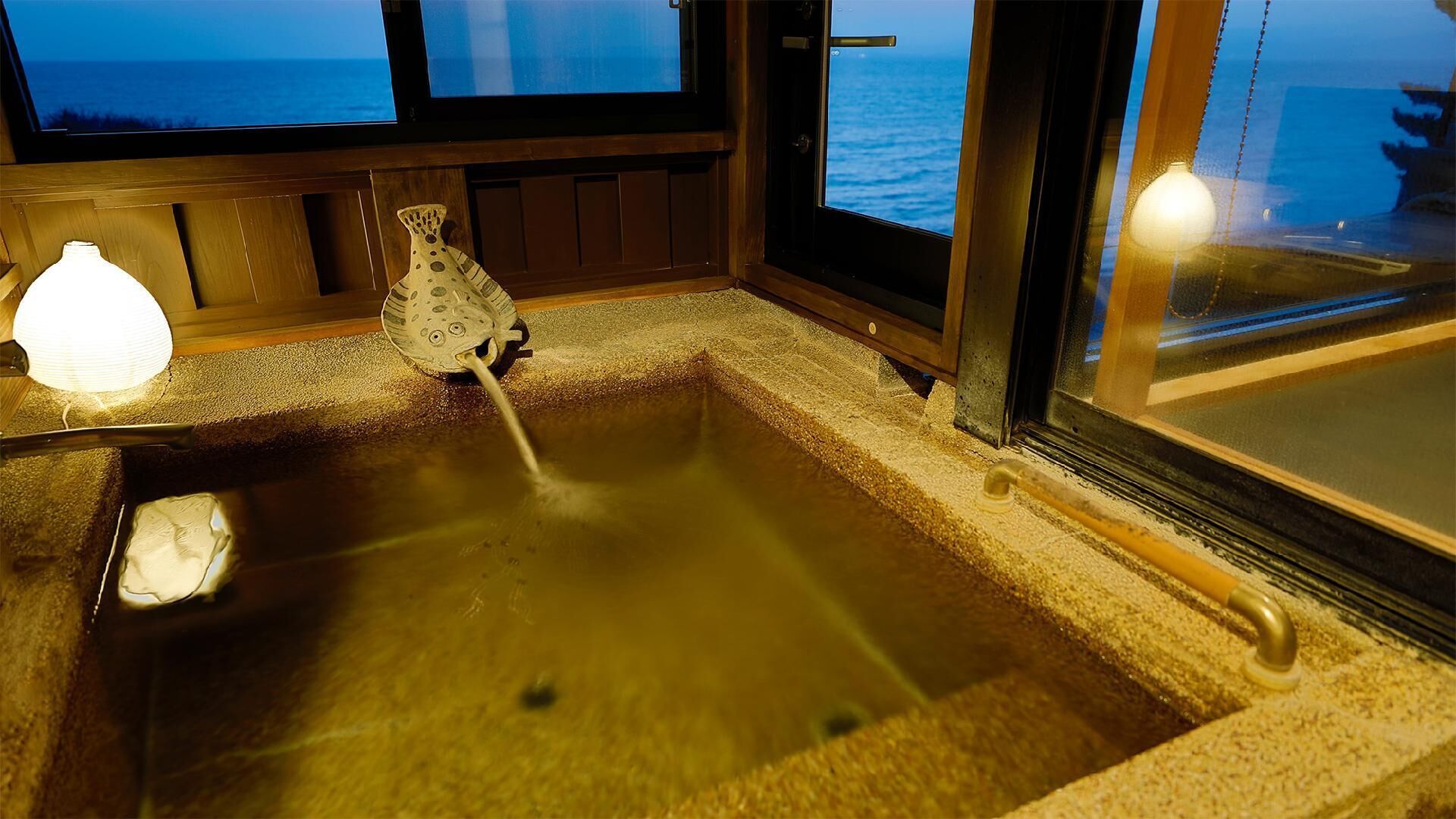 A hot spring bath with a stone basin, a small shelf, and a decorative vase.