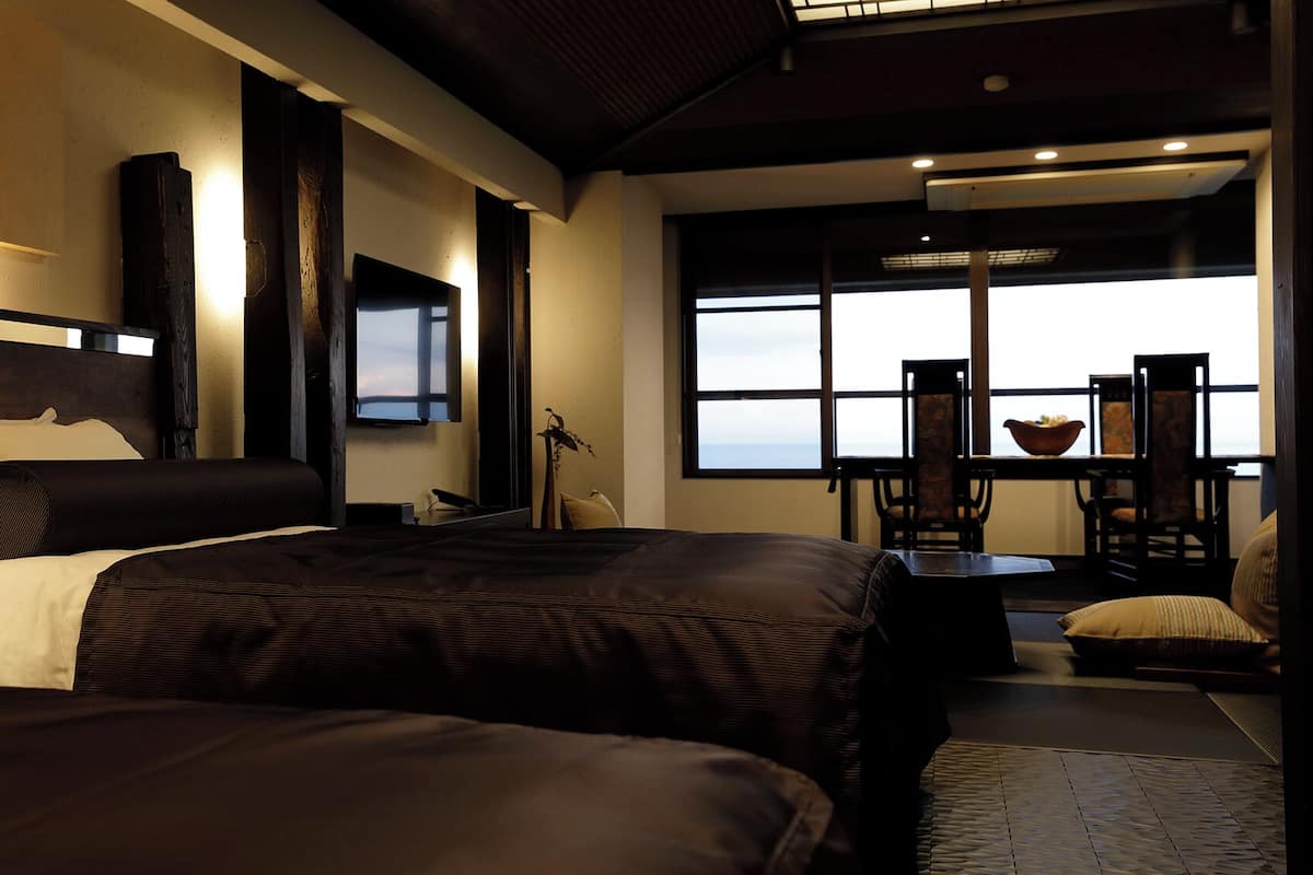 Ein modernes Hotelzimmer mit einem großen Bett, einem Schreibtisch und Blick ins Freie.