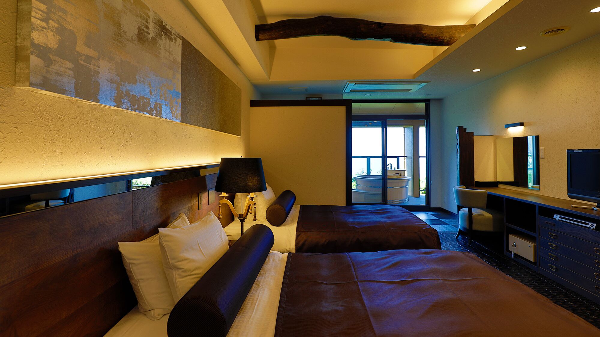 A hotel room with a large bed, a desk with a TV, a bathroom with a bathtub, and a view of the outdoors.