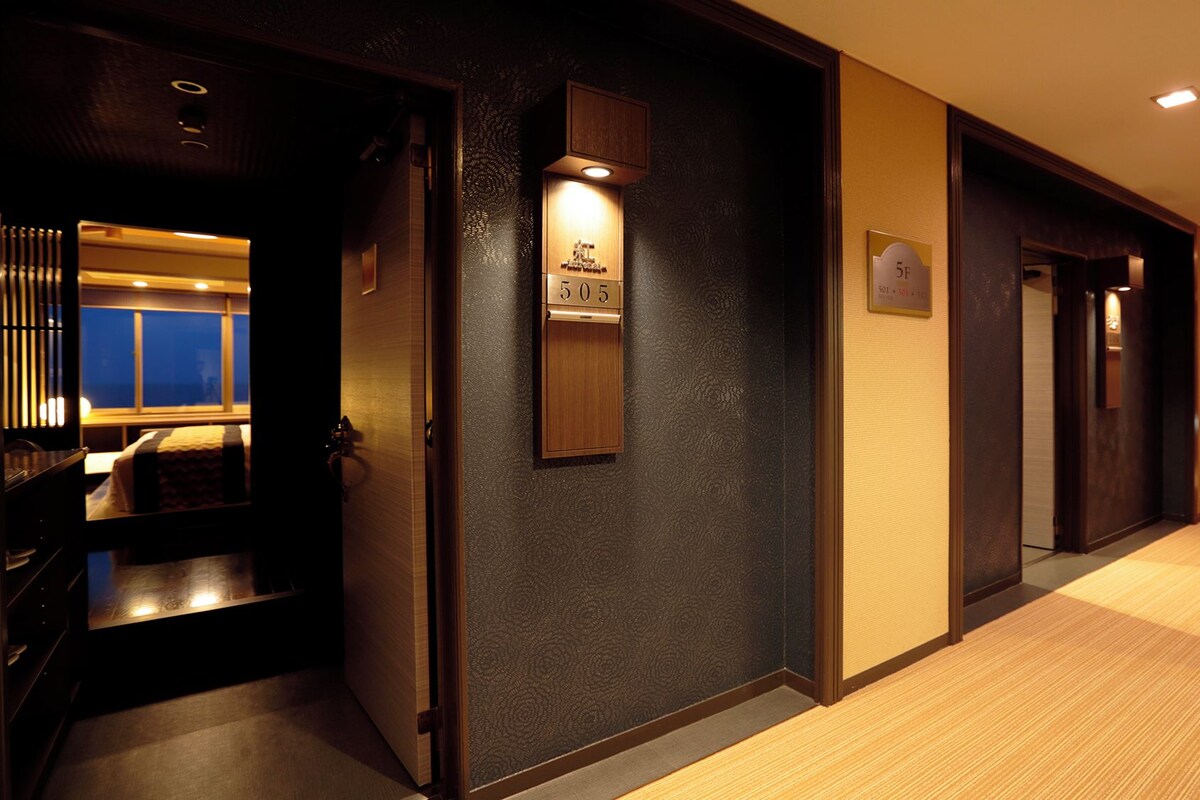 A hotel hallway with a wooden door, a reception area, and a sign indicating room number 505.