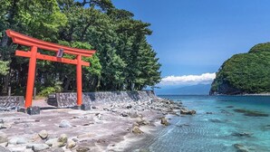 A coastal area with a red torii gate, clear turquoise waters, and a rocky beach. - Umi No Hotel Isaba (Numazu)