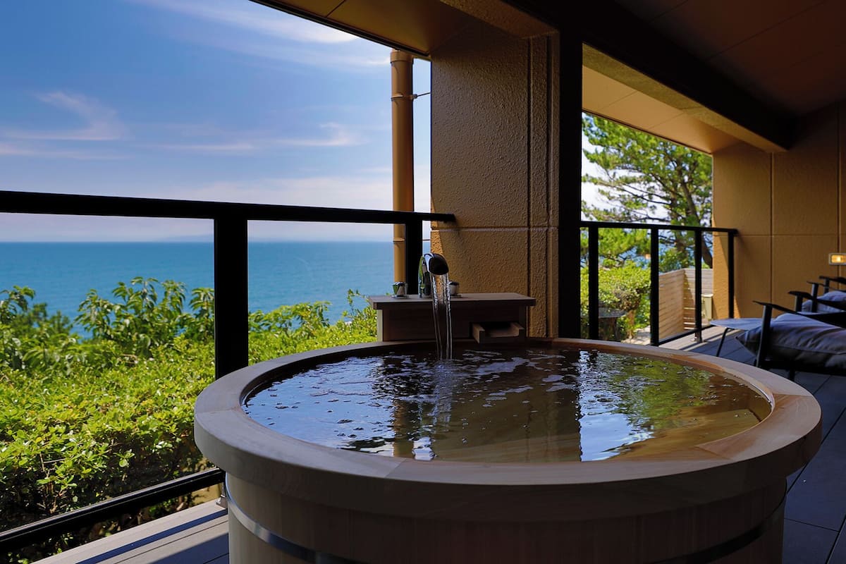 Ein Whirlpool mit Meerblick, eine Sitzecke mit Tisch und Stühlen sowie ein Balkon mit Geländer.