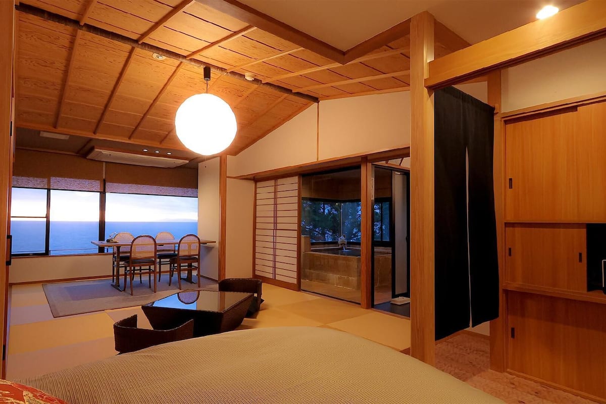 Ein Zimmer mit Meerblick, einem Essbereich mit Stühlen und einer Schiebetür zum Balkon.