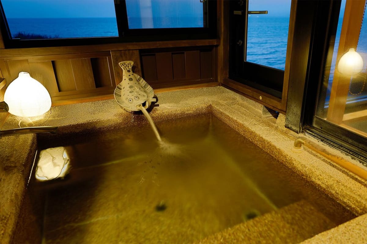 Ein Whirlpool mit Blick auf das Meer, ein kleiner Tisch mit einer Lampe und eine dekorative Vase.