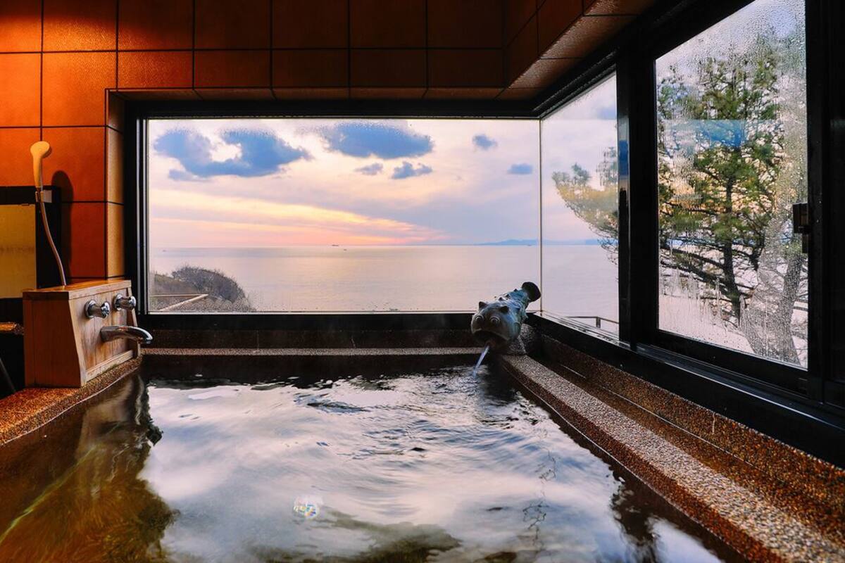 Ein Whirlpool mit Meerblick, eine Holzbank und ein Handtuchhalter.