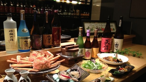 A bar area with various bottles, seafood dishes, and a sushi platter. - Station Hotel Au (Tsu)