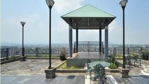 A gazebo with a green roof, surrounded by stone flooring, and two street lamps. - Station Hotel Au (Tsu)