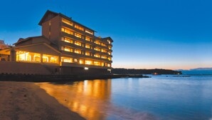 A multi-story hotel with a waterfront view, featuring balconies and a reflective pool. - Izu Mitsuhama Syoutoukan (Numazu)