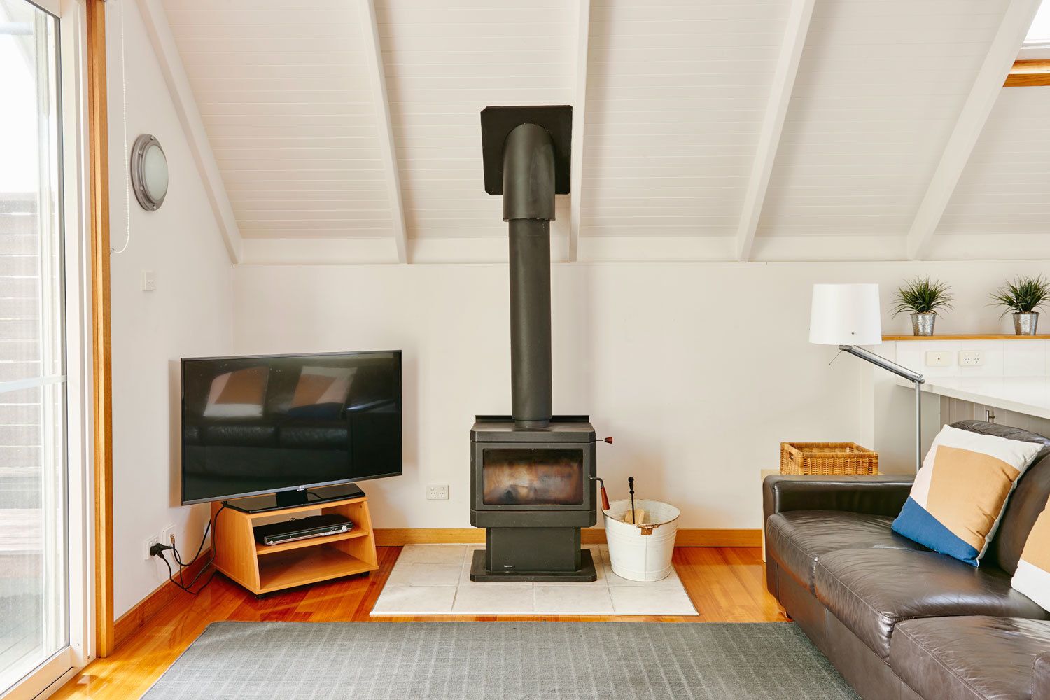 A cozy living room with a television, a fireplace, a sofa, and a small wooden cabinet.