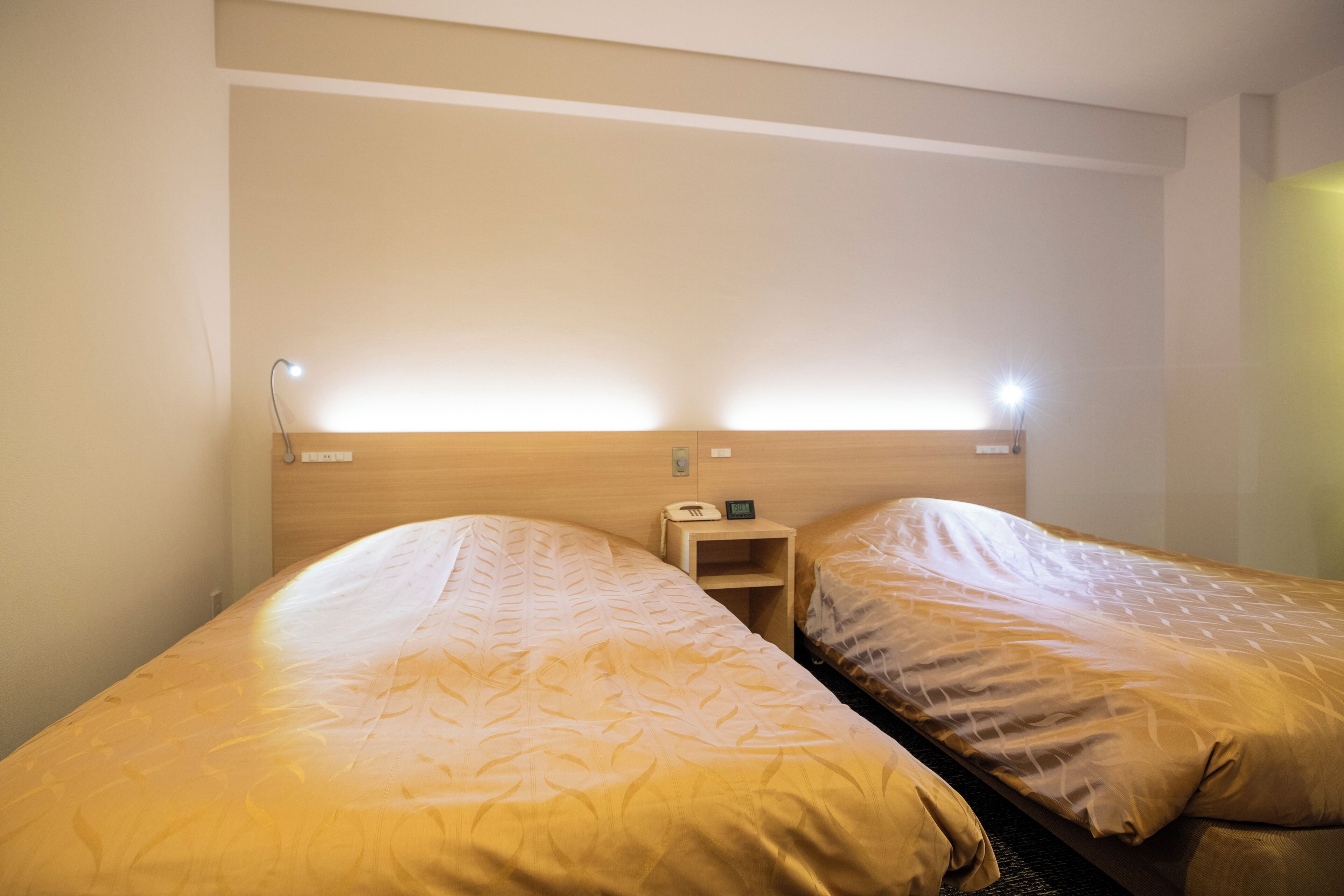 A hotel room with two single beds, each with a headboard and bedside table.