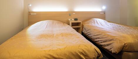 Habitación de hotel con dos camas individuales, cada una con cabecera y mesita de noche.