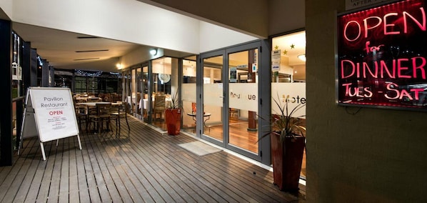 An outdoor dining area with a sign indicating the restaurant is open for dinner from Tuesday to Saturday.