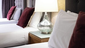 A hotel room with two beds, a nightstand with a lamp, and a textured wall.
