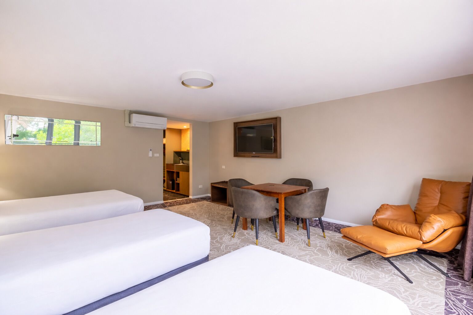 Una camera d'albergo con due letti, un tavolo da pranzo con sedie, una TV e vista sull'esterno.