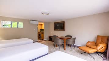 Una camera d'albergo con due letti, un tavolo da pranzo con sedie, una TV e vista sull'esterno.