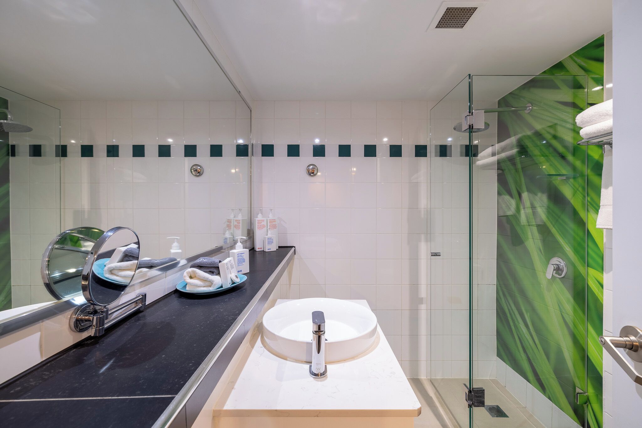 Une salle de bain moderne avec une douche à parois de verre, un lavabo rond et un meuble-lavabo avec un miroir.