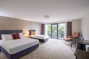 A hotel room with two beds, a balcony, a dining table, and a chair. - Mandala Signature Berry (Berry)