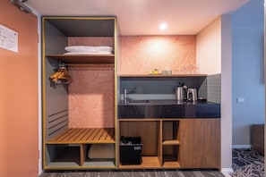 A compact kitchenette with a sink, a coffee maker, and a small countertop. - Mandala Signature Berry (Berry)