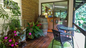 A wooden deck with a table and chairs, surrounded by potted plants and flowers.