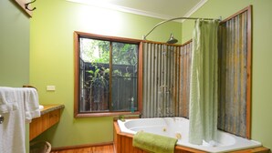 Un baño con bañera de madera, una ventana y cortina de ducha.