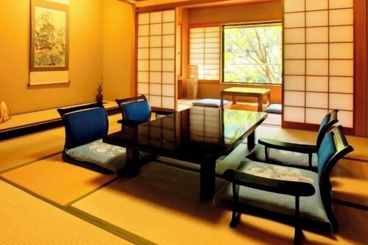 A traditional Japanese room with tatami flooring, a low table, and chairs.