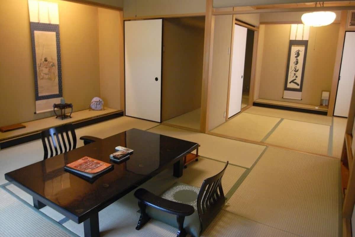 A traditional Japanese room with tatami flooring, a low table, and sliding doors.