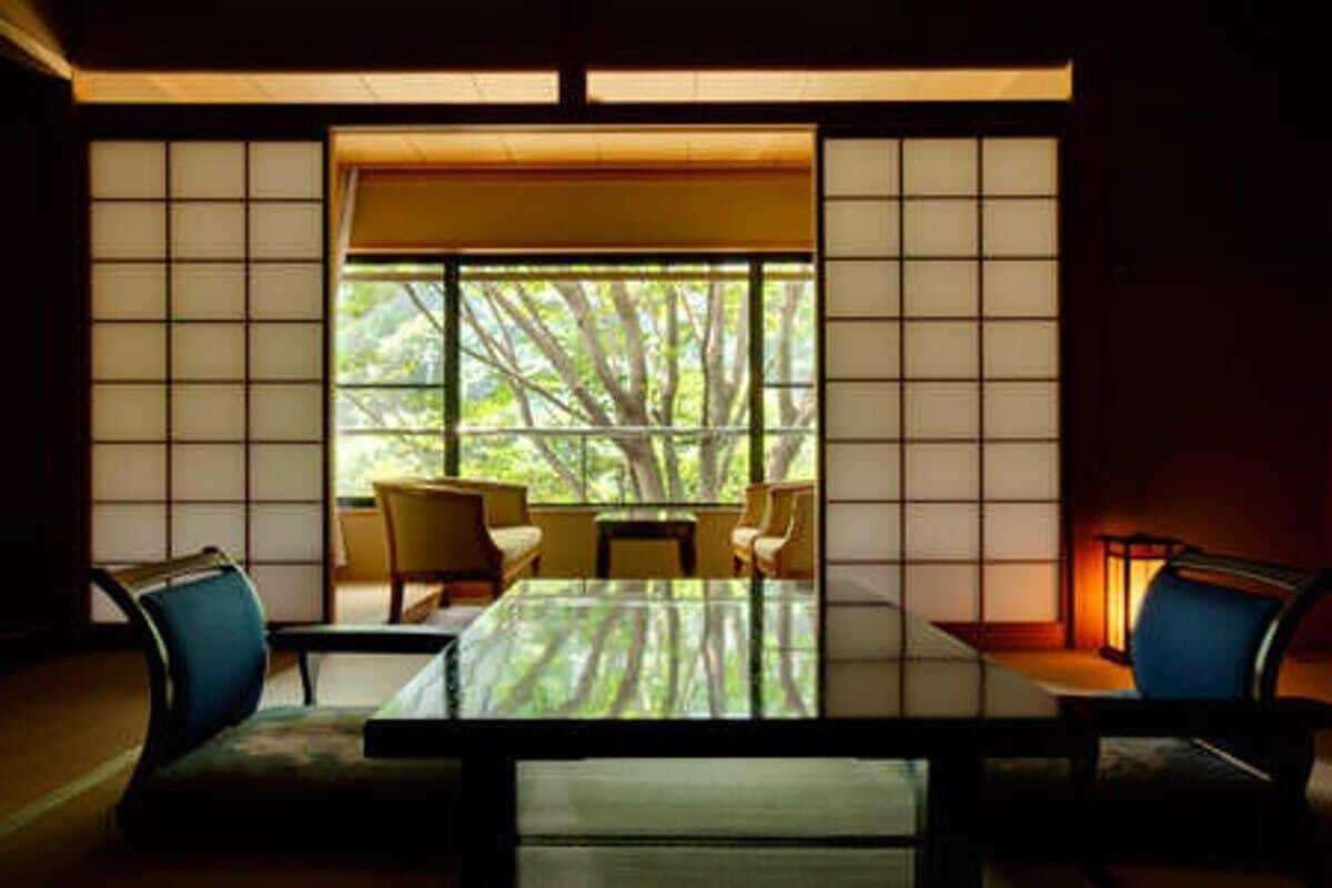A traditional Japanese-style room with tatami flooring, a low table, and chairs.