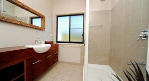 Un baño moderno con un lavabo grande, tocador y ducha a pie.