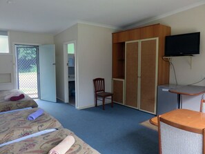 A hotel room with two beds, a desk, a chair, a television, and a wardrobe. - Ecotel Narooma (North Narooma)