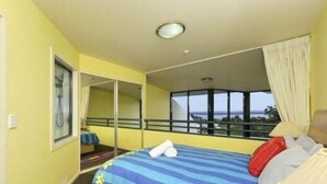 A hotel room with a bed, a window with a view, a mirror, and a shower. - Bali in Broughton (Nelson Bay)