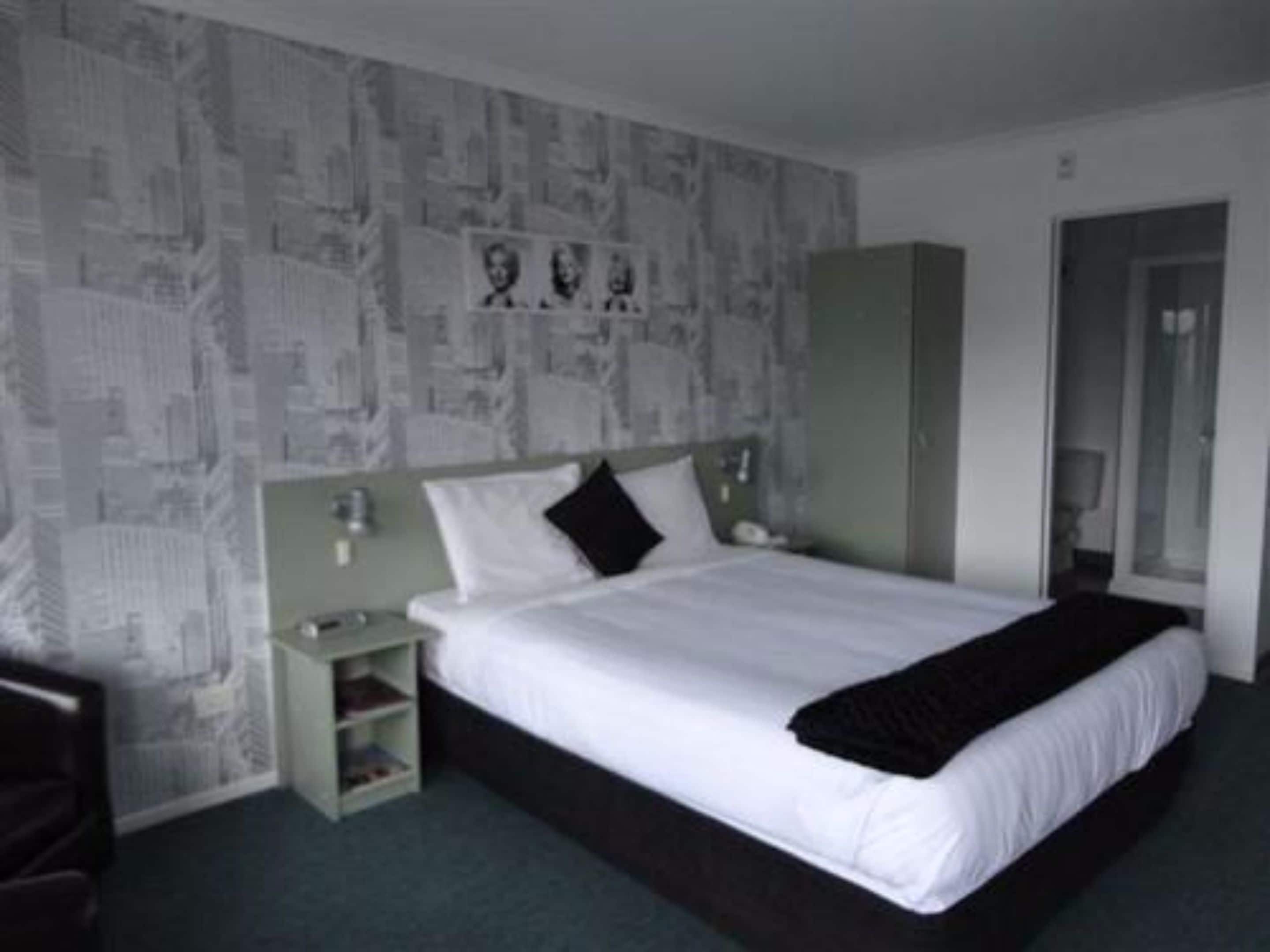A bedroom with a bed, a nightstand, a wardrobe, and a mirror.