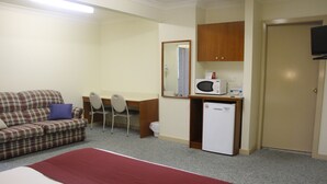 A room with a bed, a desk, a chair, a microwave, a small refrigerator, and a television. - Pioneer Way Motel (Faulconbridge)