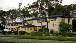 A motel with a two-story structure, a signboard, and a well-maintained lawn. - Pioneer Way Motel (Faulconbridge)