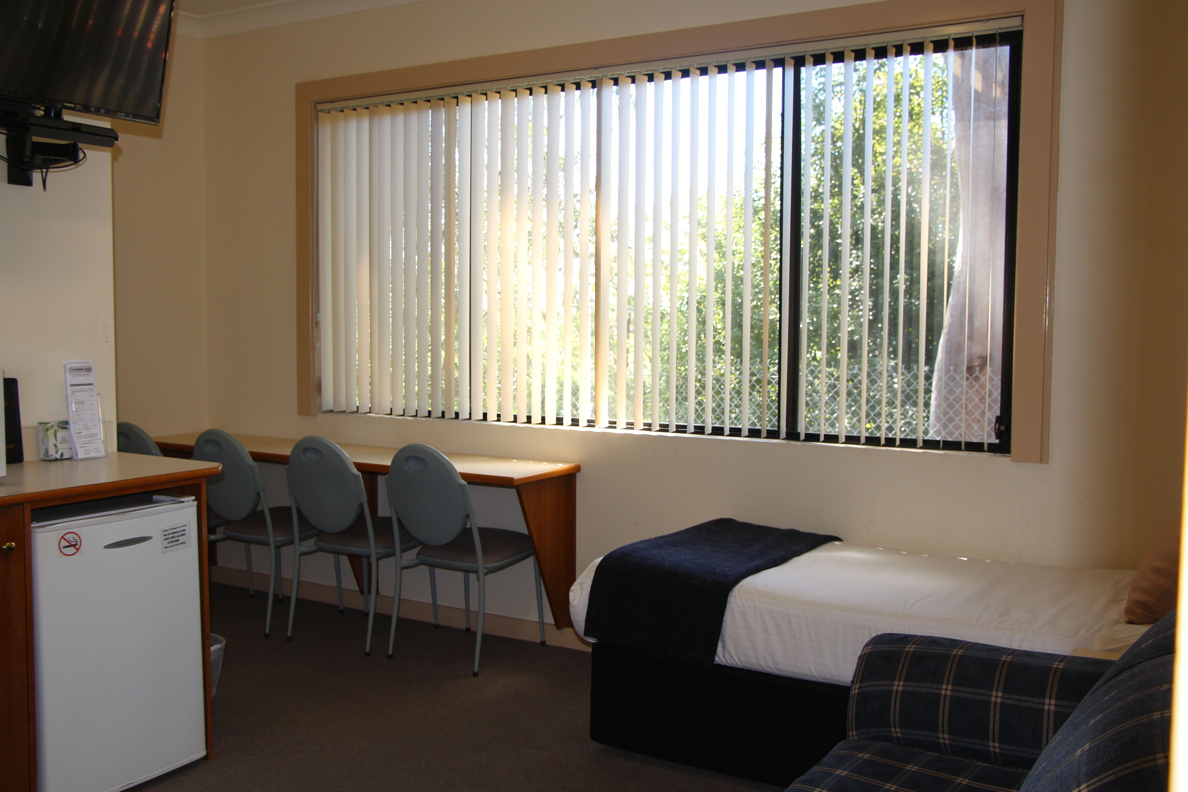 A room with a bed, a desk, and chairs.