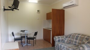 A compact living space with a kitchenette, a dining area, and a sofa. - Pioneer Way Motel (Faulconbridge)
