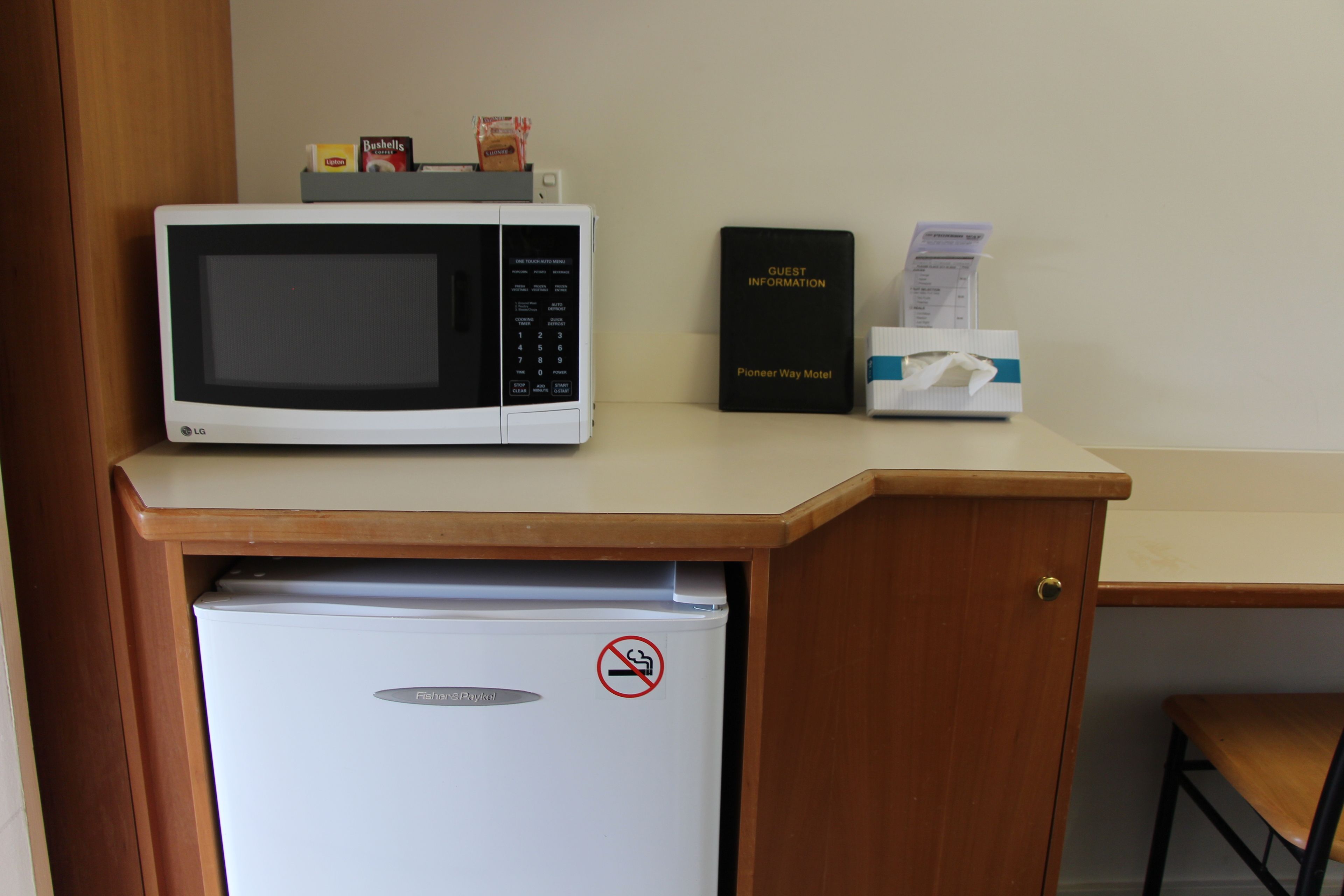 A microwave, a guest information booklet, and a tissue box on a counter.